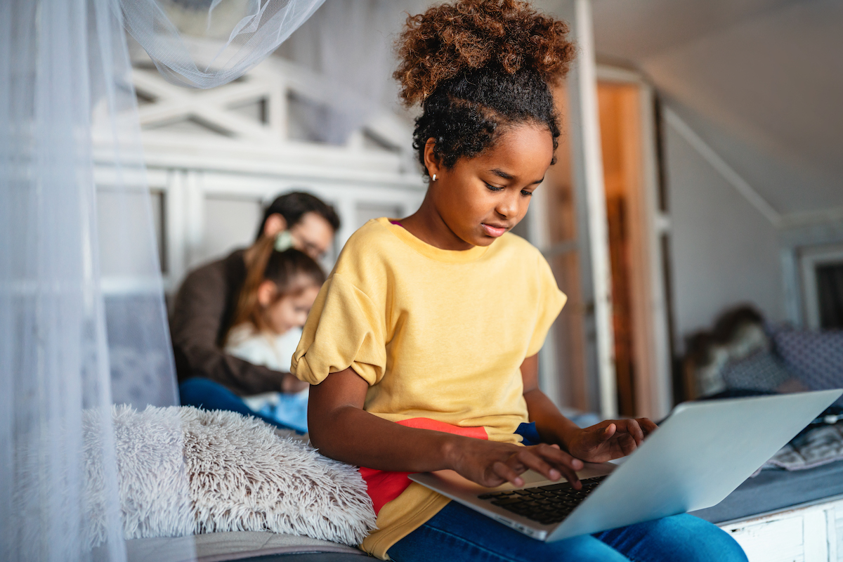 Happy black schoolgirl studying online at home. Education and knowledge modern technology concept